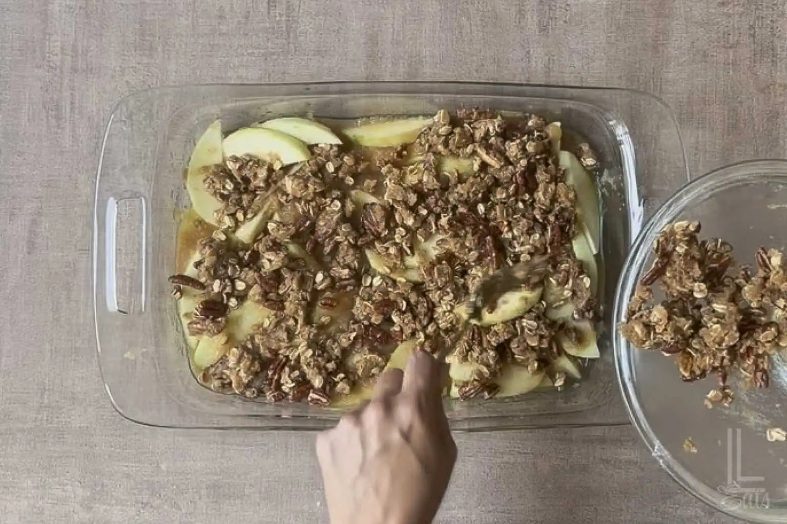 adding the pecan oat topping to the applesauce crisp.