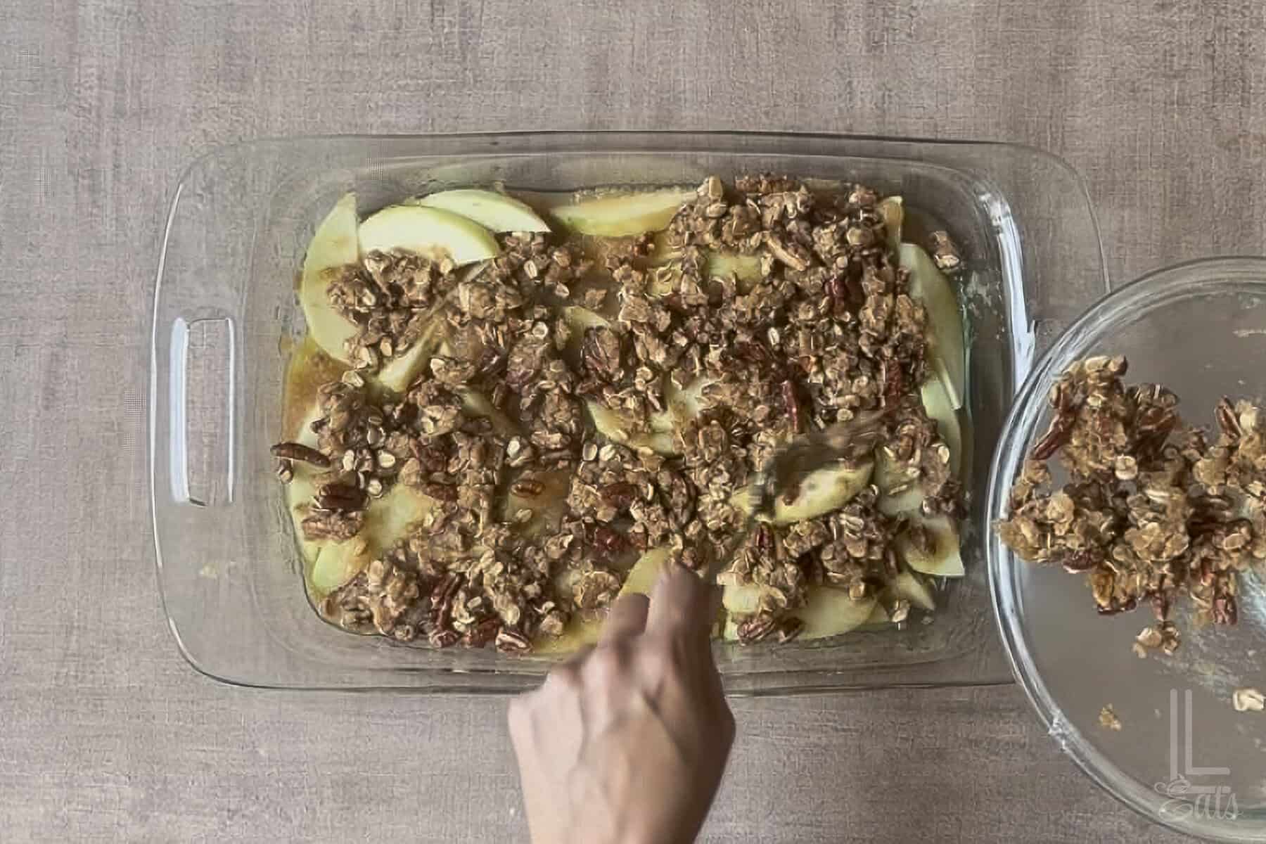 adding the pecan oat topping to the applesauce crisp.