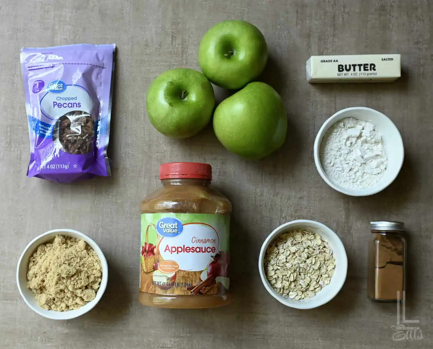 Ingredients for applesauce crisp with oats including apples, oats, cinnamon, butter, and pecans.