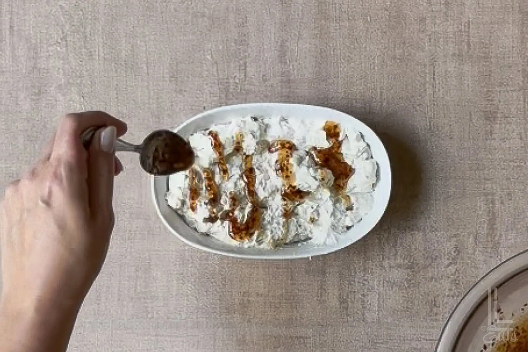 drizzling hot honey over the creamy base for hot honey dip in a ceramic dish.