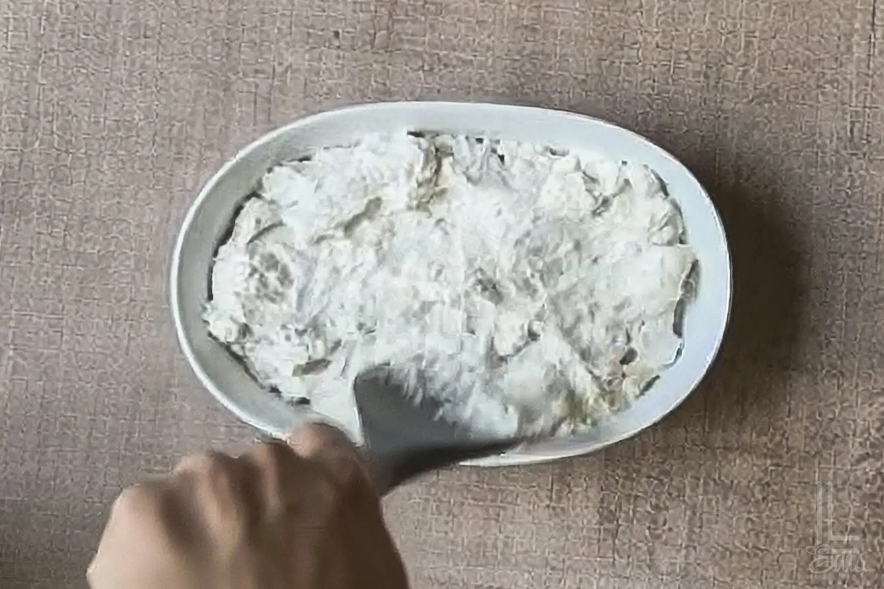 spreading the cream cheese and sour cream mixture in a small ceramic dish.