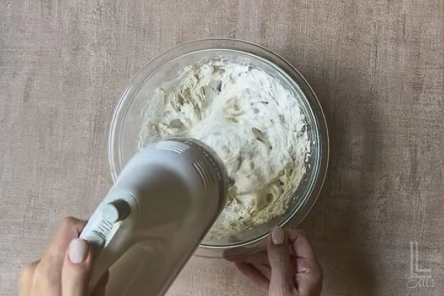 Mixing cream cheese and sour cream for creamy hot honey dip in a glass bowl with a hand blender.