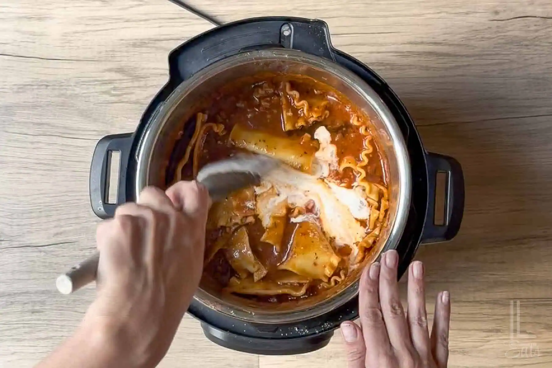 Adding heavy cream to the cooked lasagna soup in the instant pot.