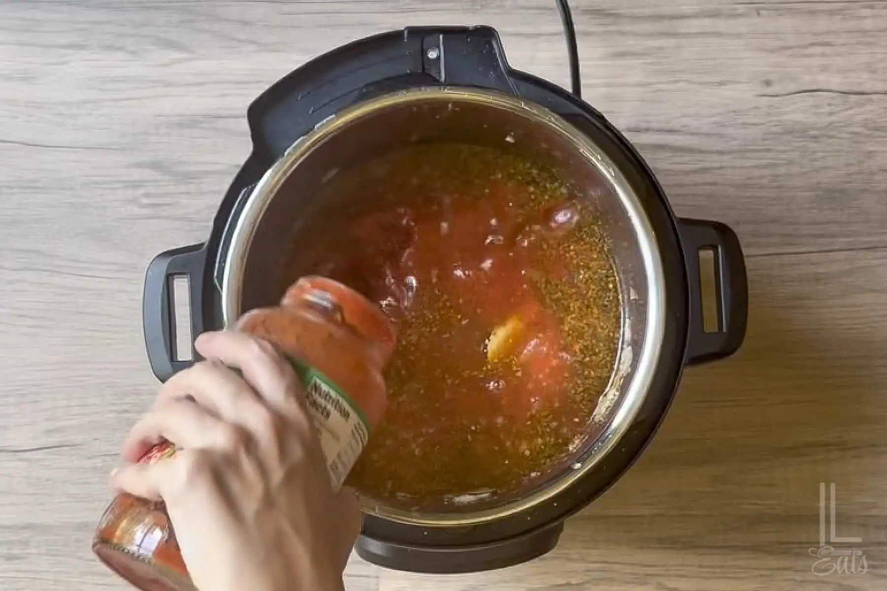 Adding pasta sauce to an Instant Pot for lasagna soup recipe.