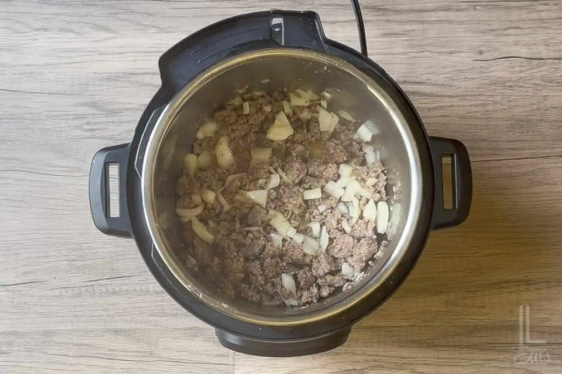 Italian sausage, onions, and garlic cooking in an Instant Pot for lasagna soup.