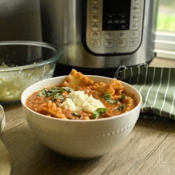 Delicious homemade lasagna soup in a white bowl with herbs and cheese.of an instant pot.