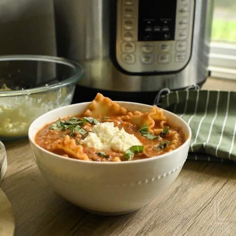 Delicious homemade lasagna soup in a white bowl with herbs and cheese.of an instant pot.
