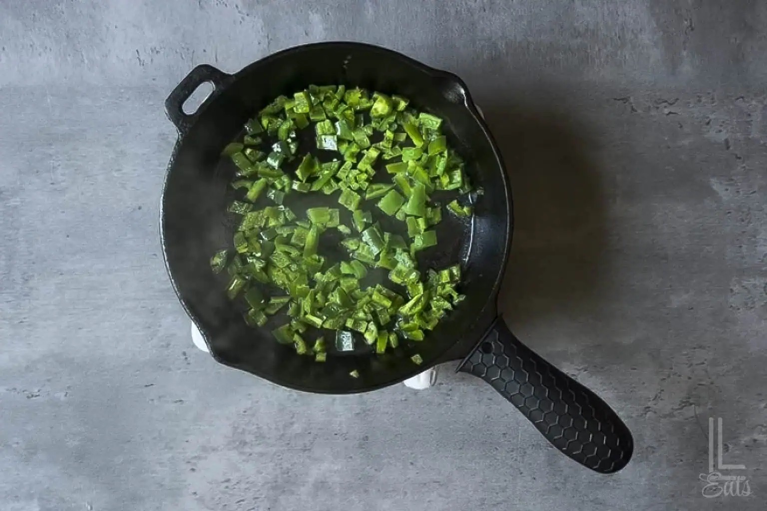 Sautéing fresh jalapeños in a cast-iron skillet.