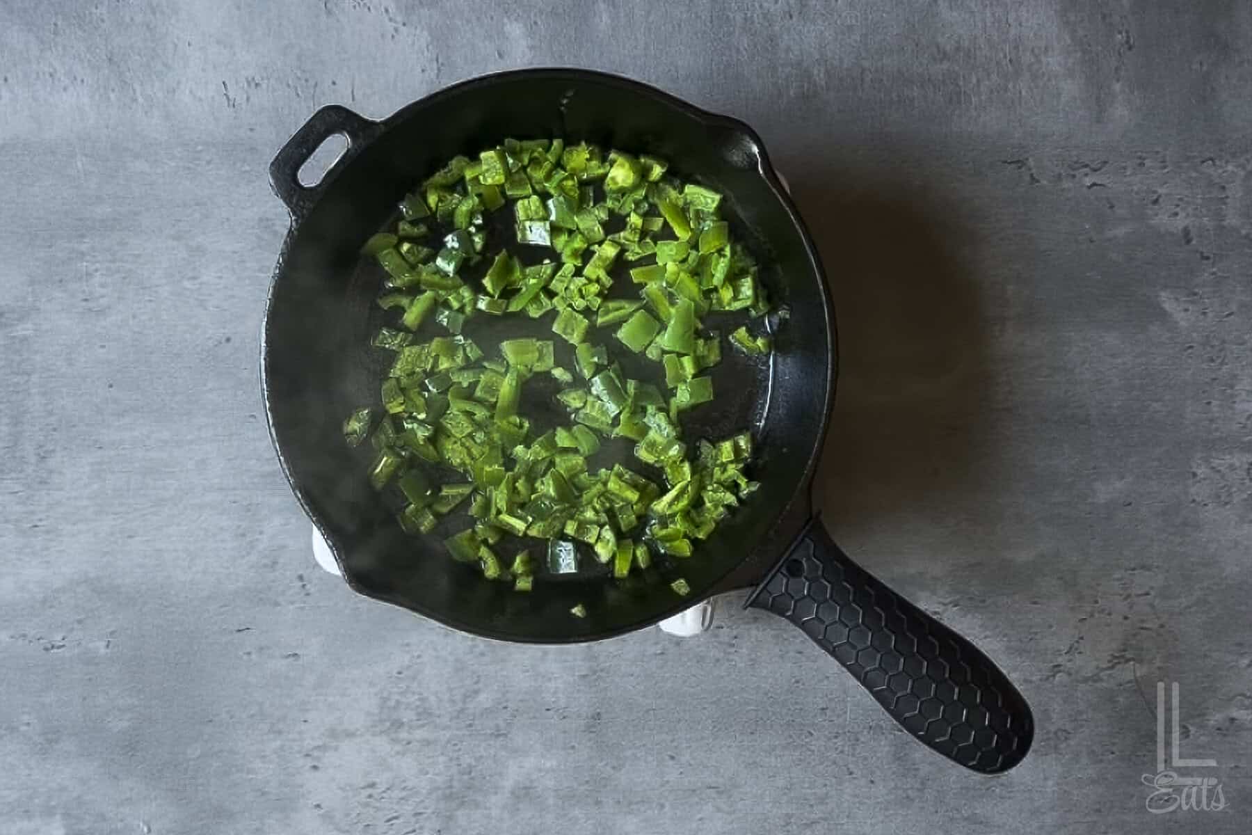 Sautéing fresh jalapeños in a cast-iron skillet.