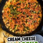 Cream cheese jalapeño popper dip in a cast iron skillet with fresh jalapeños nearby.