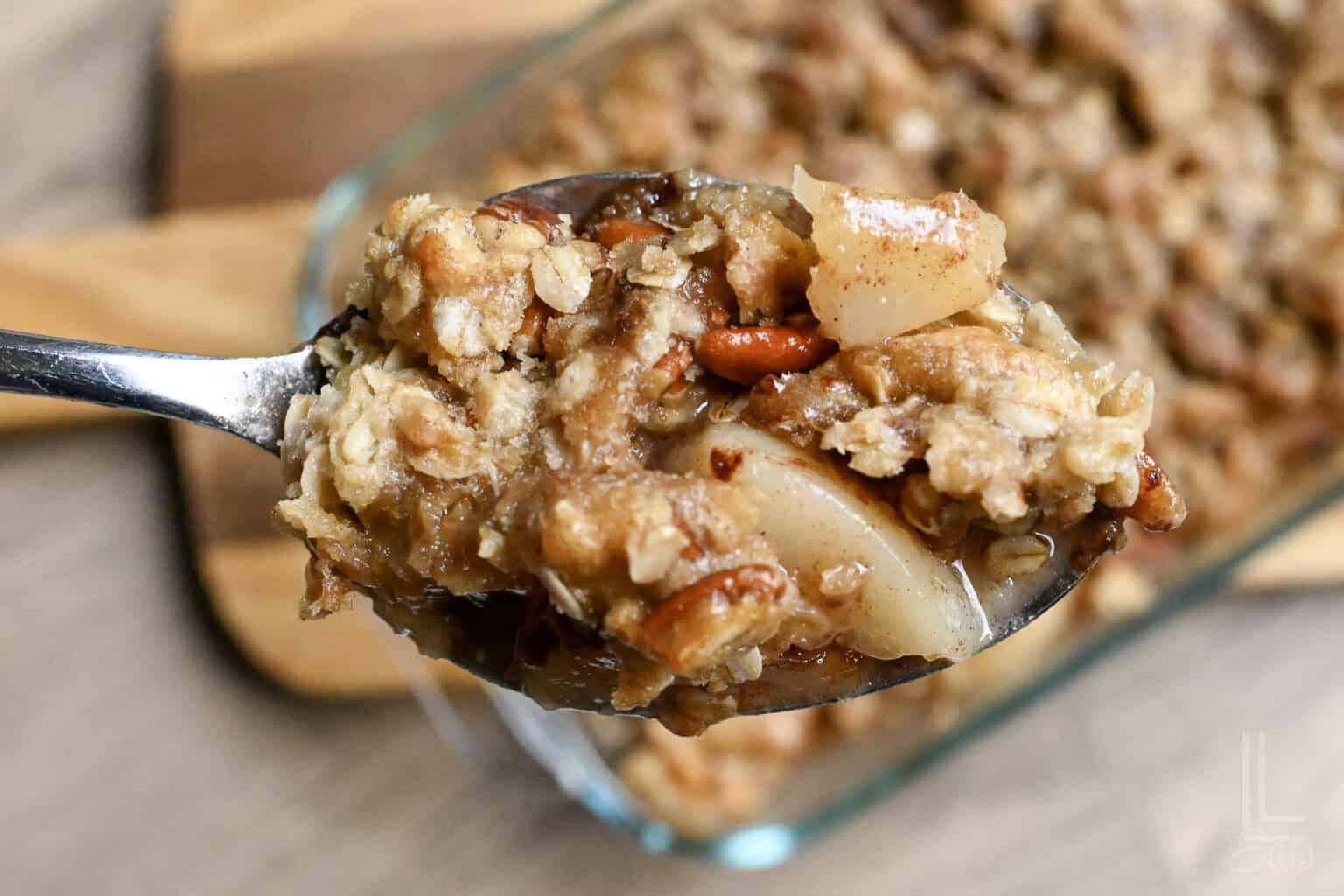 Close-up of a spoonful of pear crumble with canned pears and oats.