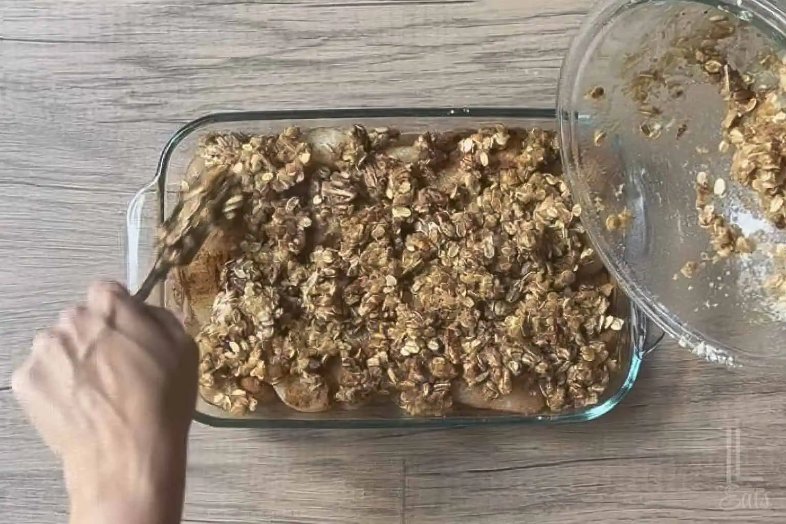 pouring the pecan crumble topping over the canned pear mixture.