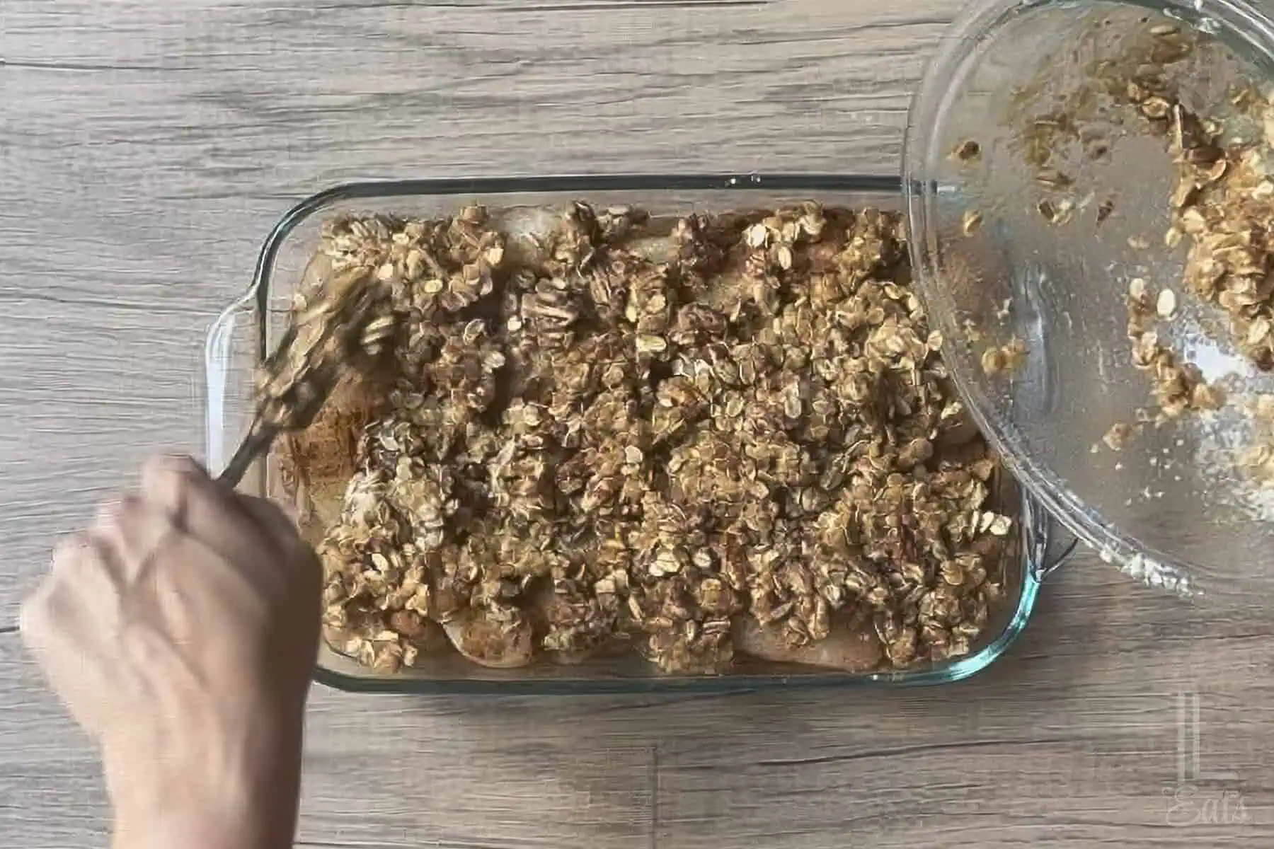 pouring the pecan crumble topping over the canned pear mixture.
