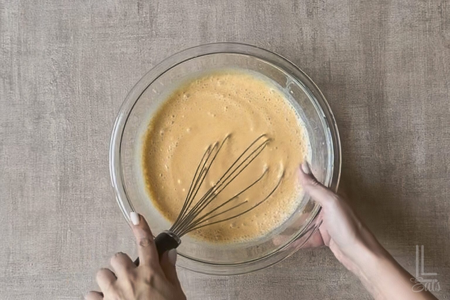 Mixing cheesecake pumpkin pudding mix in a glass bowl with a whisk.