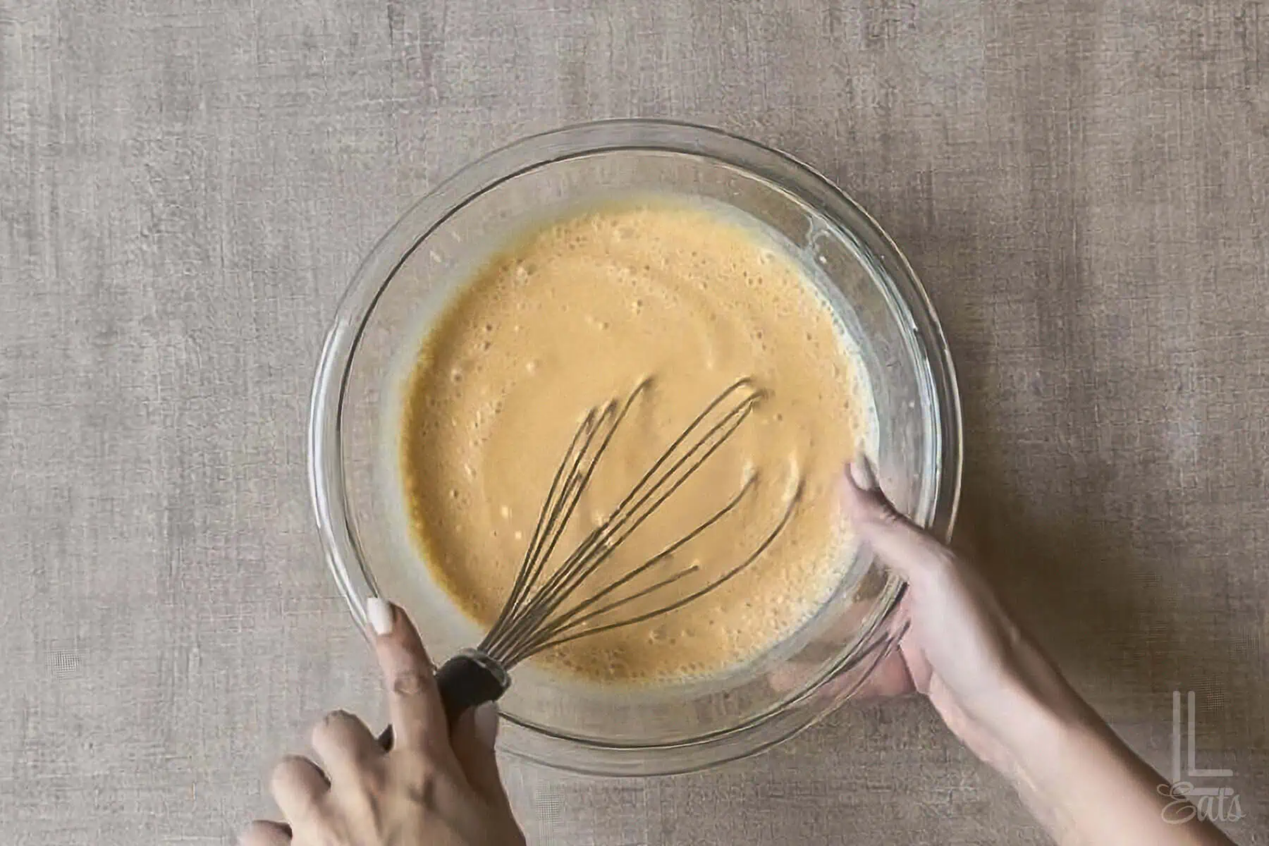 Mixing cheesecake pumpkin pudding mix in a glass bowl with a whisk.
