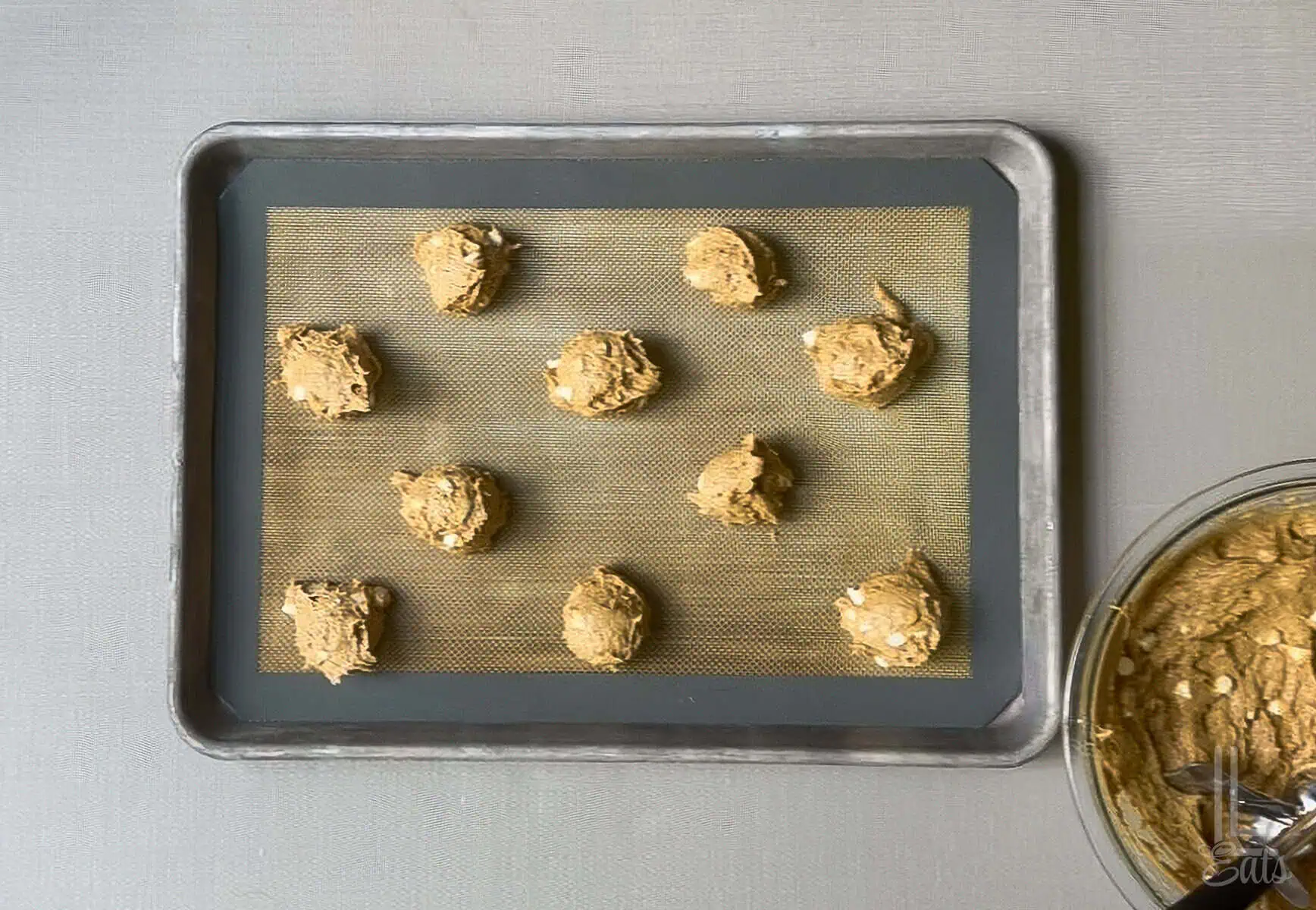 Unbaked pumpkin white chocolate chip cookies on a baking sheet ready for baking.