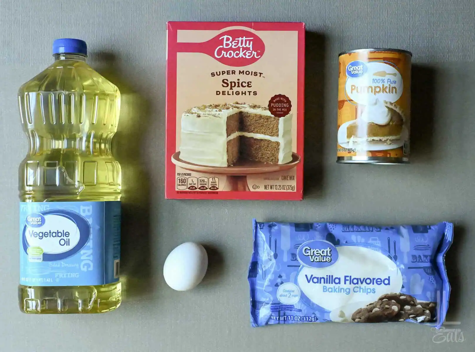 ingredients for pumpkin white chocolate chip cookies, including vegetable oil, cake mix, pumpkin, egg, and white chocolate chips.