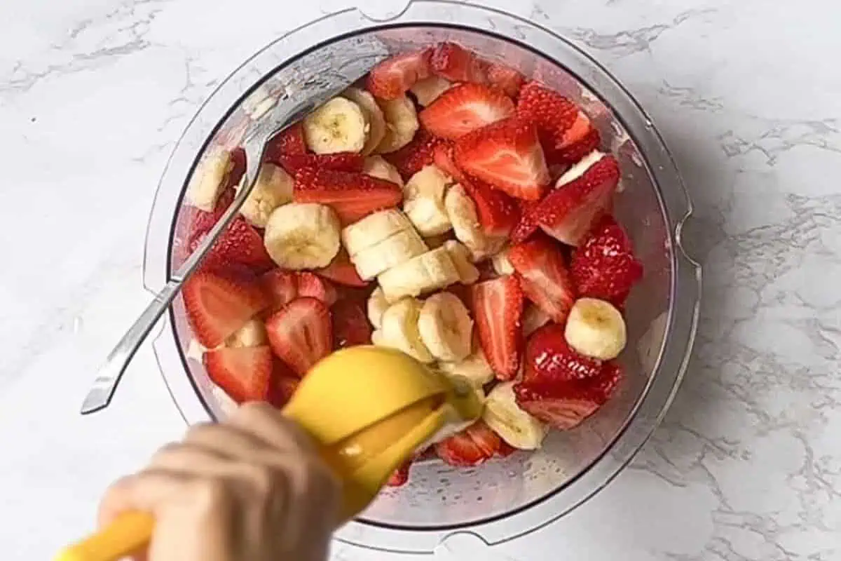 adding lemon juice to sliced strawberries and bananas.