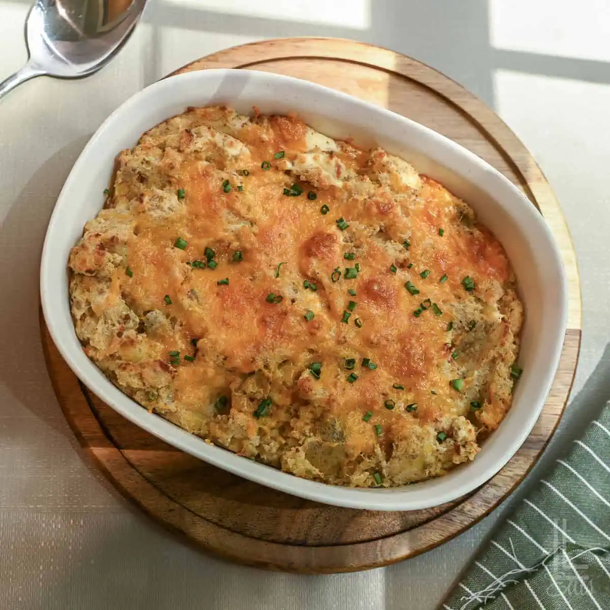 Twice baked mashed potatoes with melted cheese and green onions in a white dish.