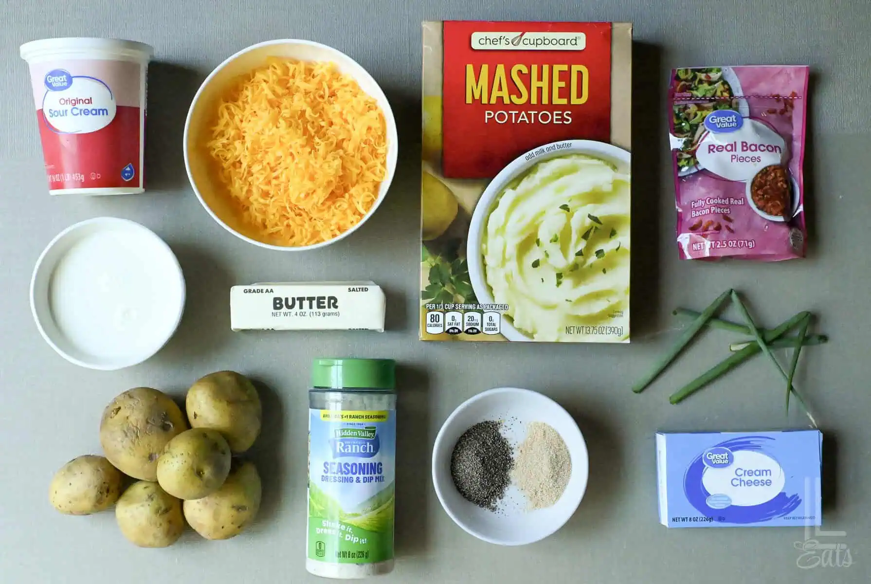 Ingredients for twice baked mashed potatoes including cheese, butter, sour cream, and potatoes.