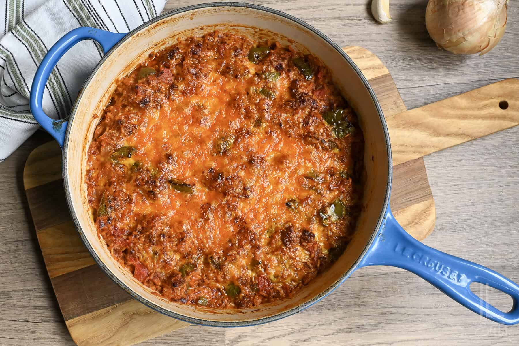 Baked unstuffed peppers in a blue skillet on a wooden board.