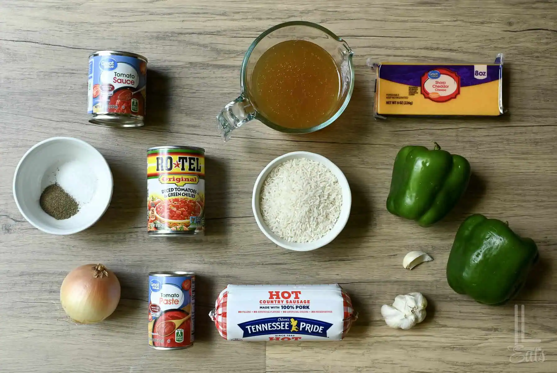 Ingredients for unstuffed peppers on a wooden surface including green peppers, rice, Rotel tomatoes,and breakfast sausage.