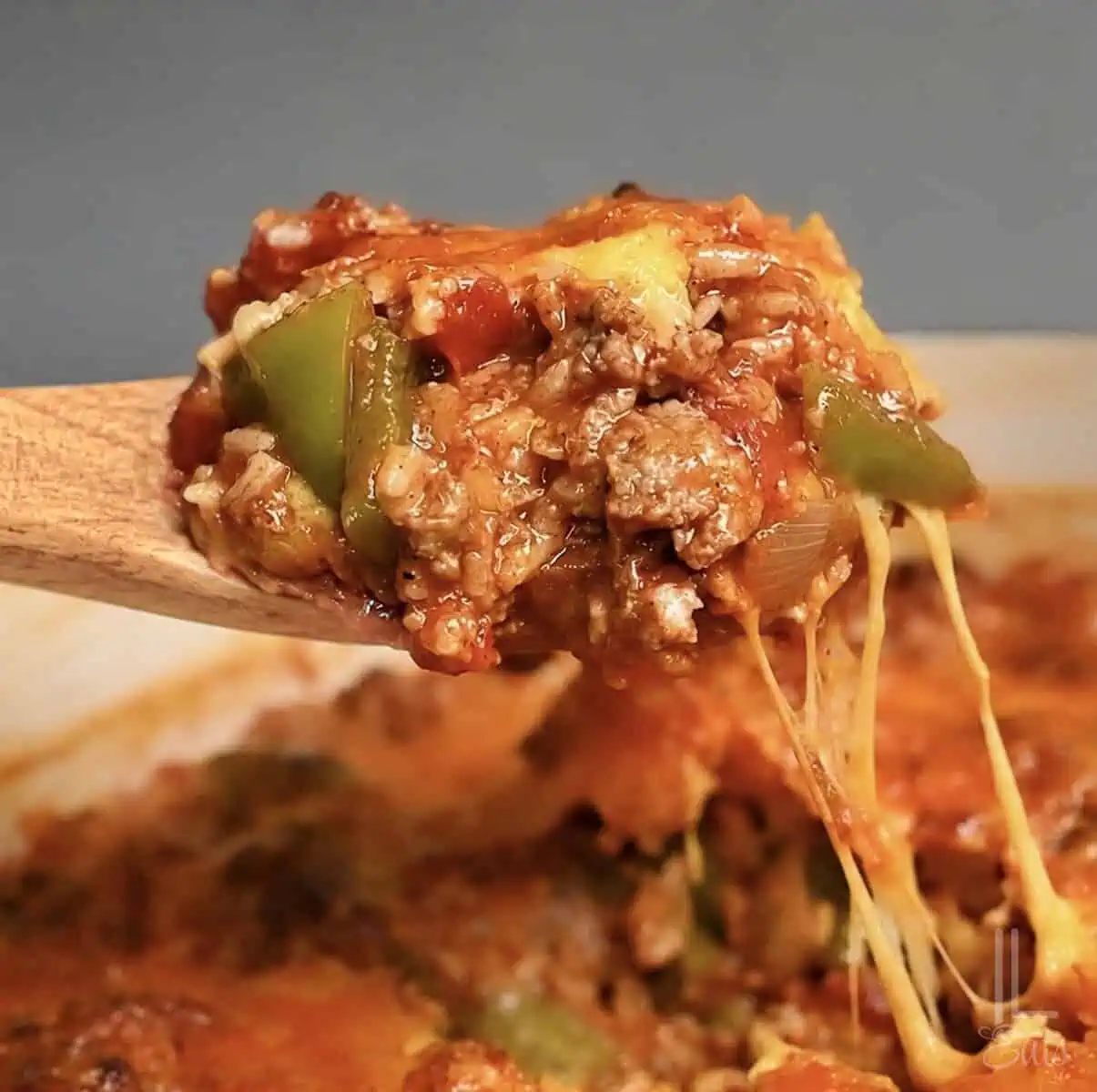 Unstuffed peppers with ground sausage, cheese, tomatoes, and green bell peppers on a spoon.