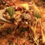 Close-up of cheesy sausage stuffed peppers with melted cheese and green peppers.