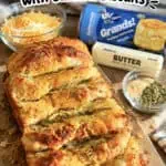 Cheesy garlic pull apart bread with canned biscuits and butter on a wooden surface.
