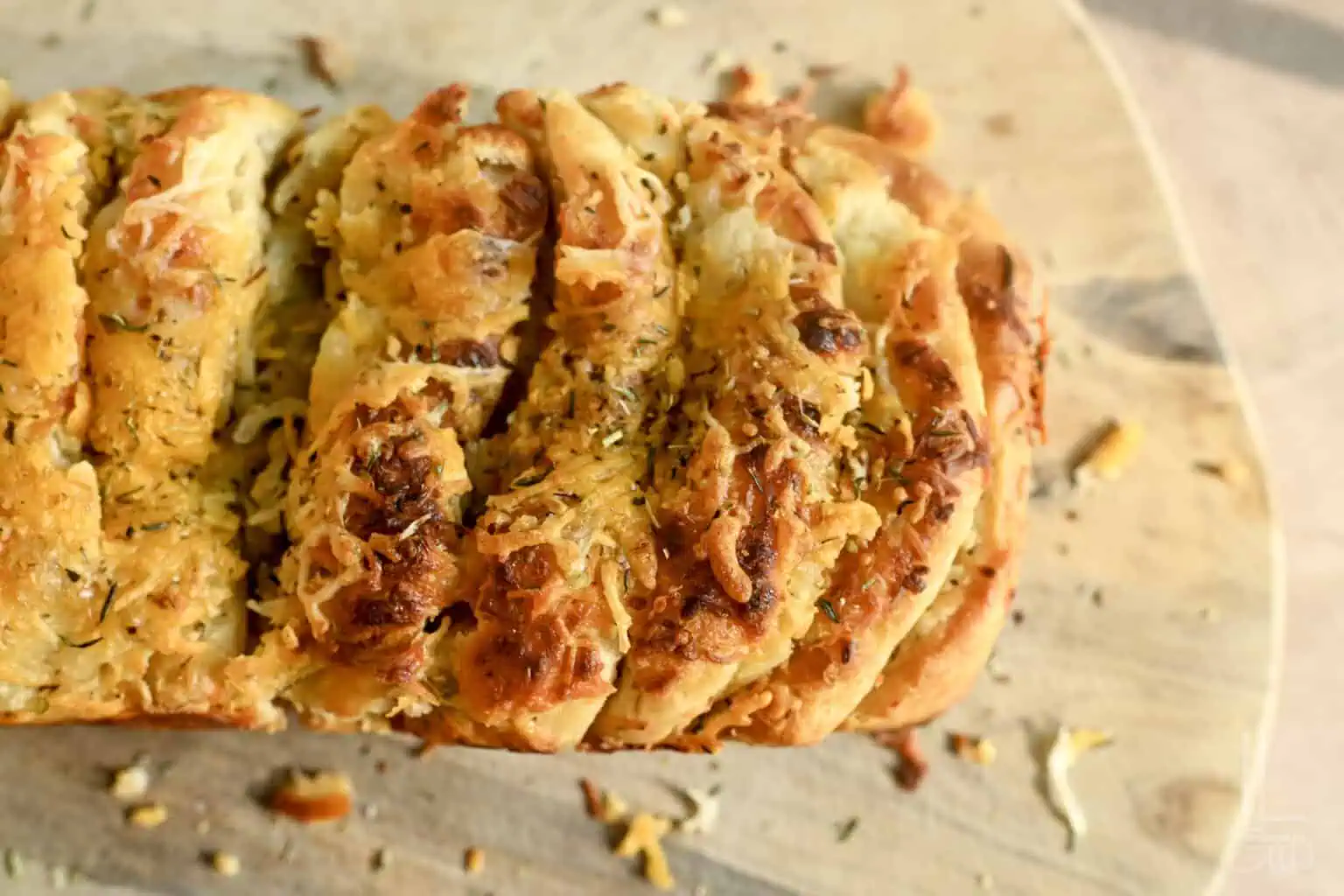 Cheesy garlic pull apart bread with golden crust on a wooden board.