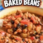 Close-up of homemade cowboy baked beans in a bowl with a spoonful lifted.