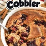 Close-up of a freshly baked cranberry spice cake cobbler in a white dish with berries around it.