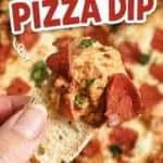 Close-up of a hand holding a slice of pizza dip on bread with a pizza in the background.