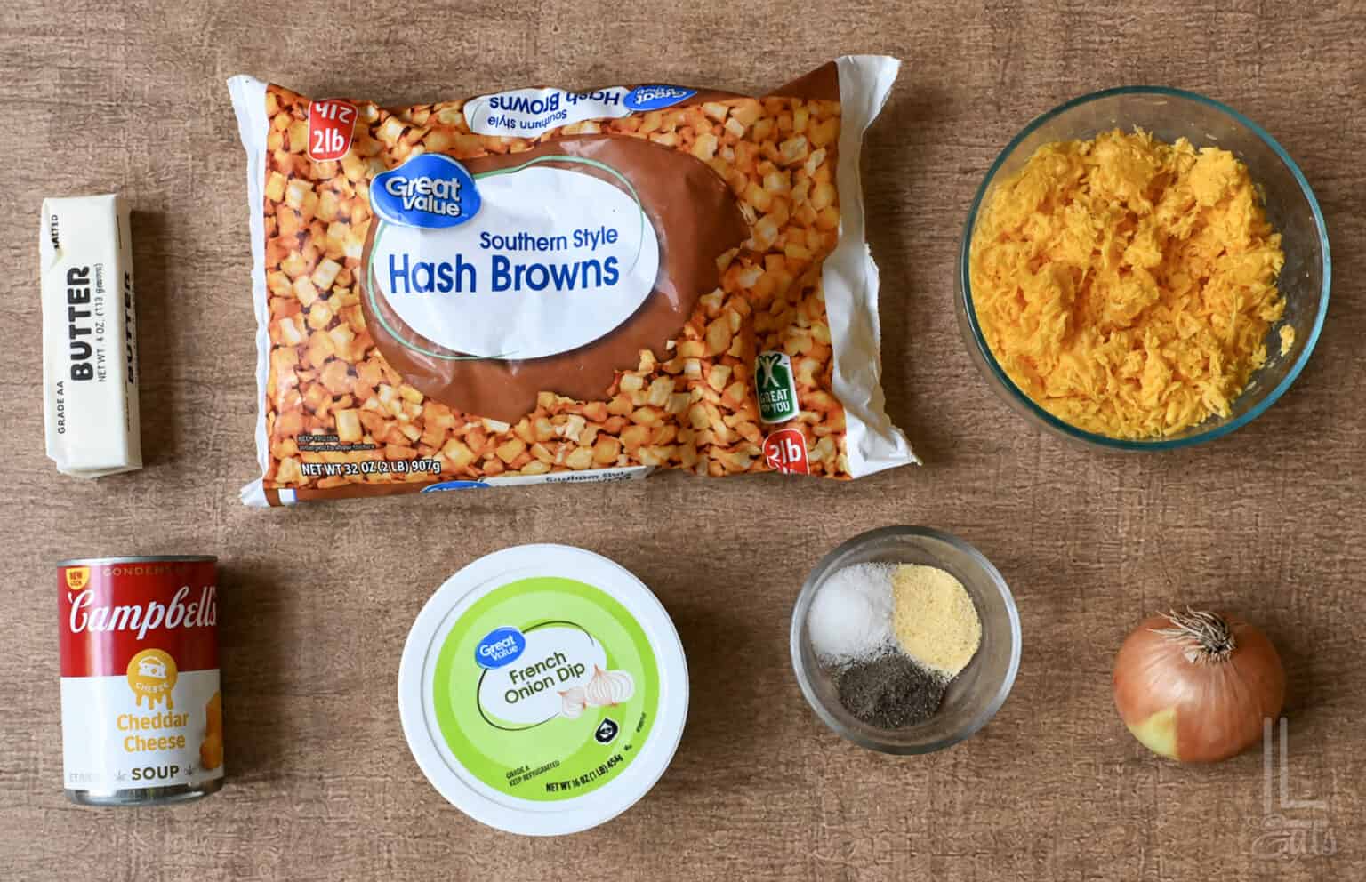 Ingredients for cheesy potatoes including hash browns, cheddar cheese, onion, butter, and seasonings.