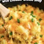 Close-up of cheesy potatoes with cheddar cheese and green onions in a crockpot.