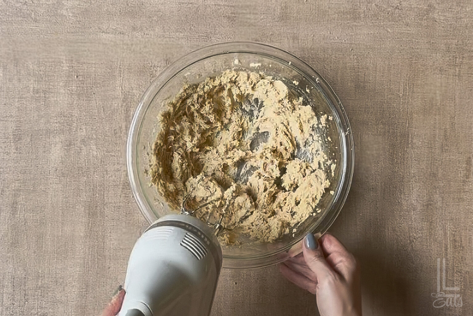 Mixing butter and brown sugar in a glass bowl.