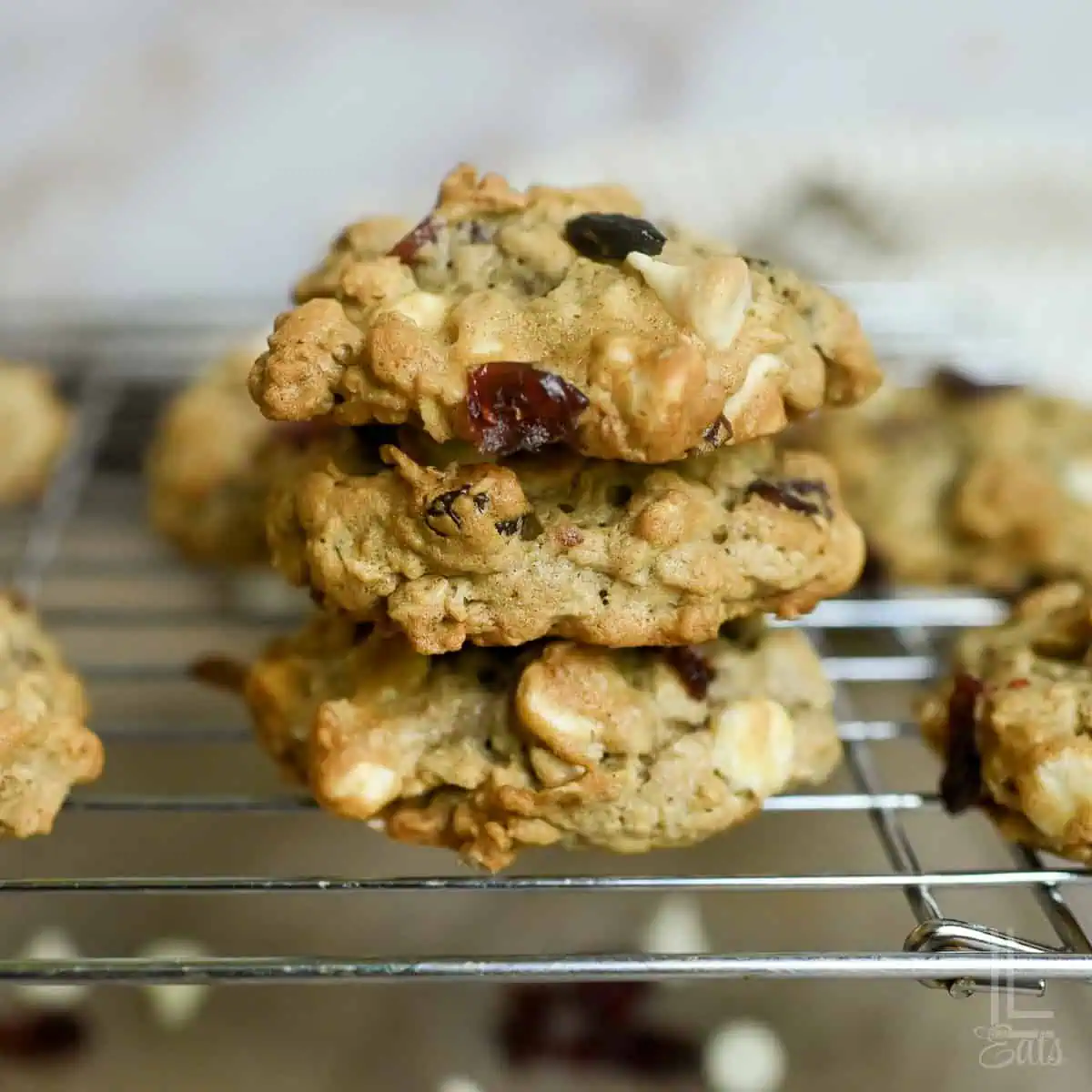 Close-up of oatmeal cranberry cookies with white chocolate stacked on a cooling rack.