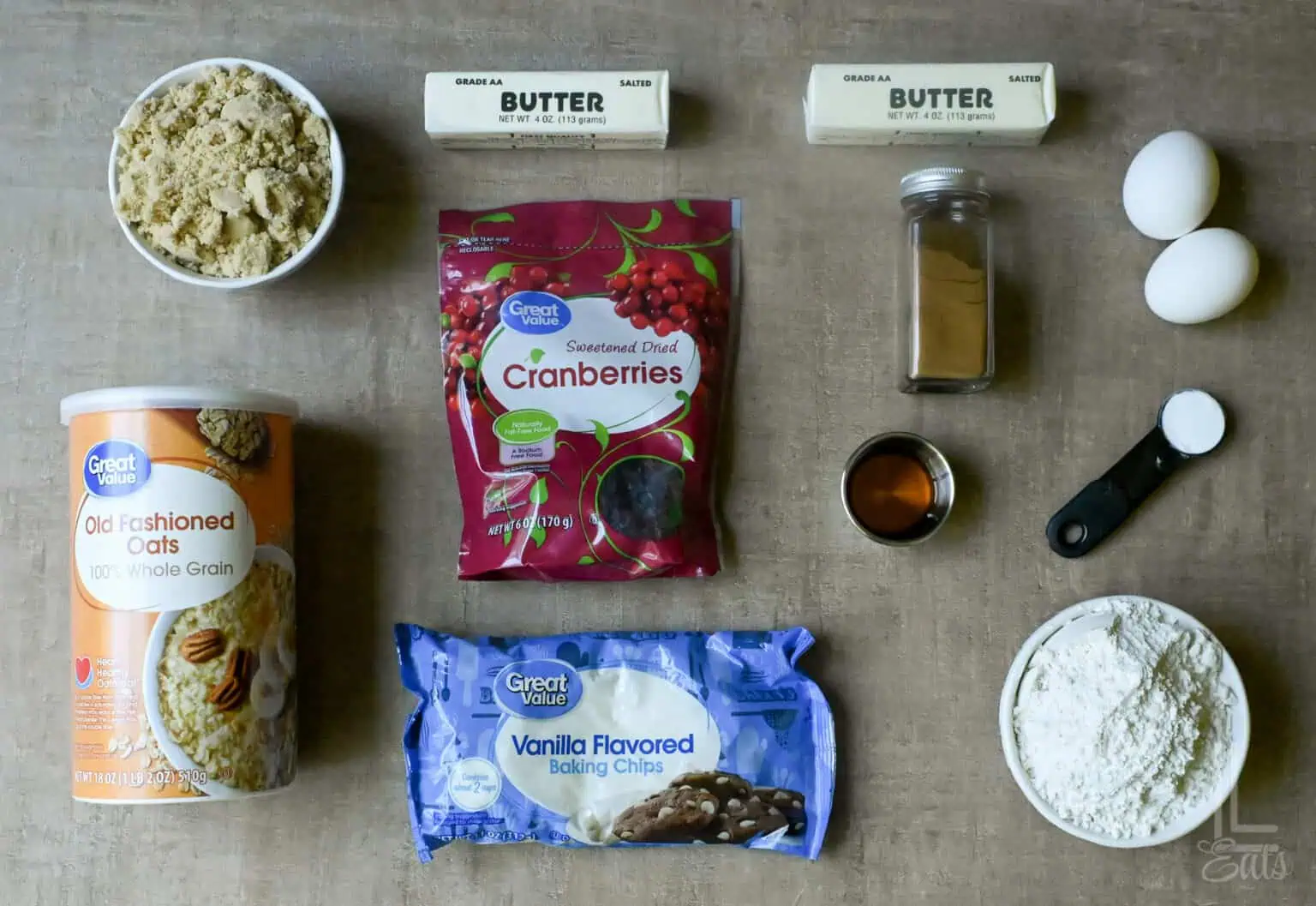 Ingredients for oatmeal cranberry cookies with white chocolate chips on a flat surface.