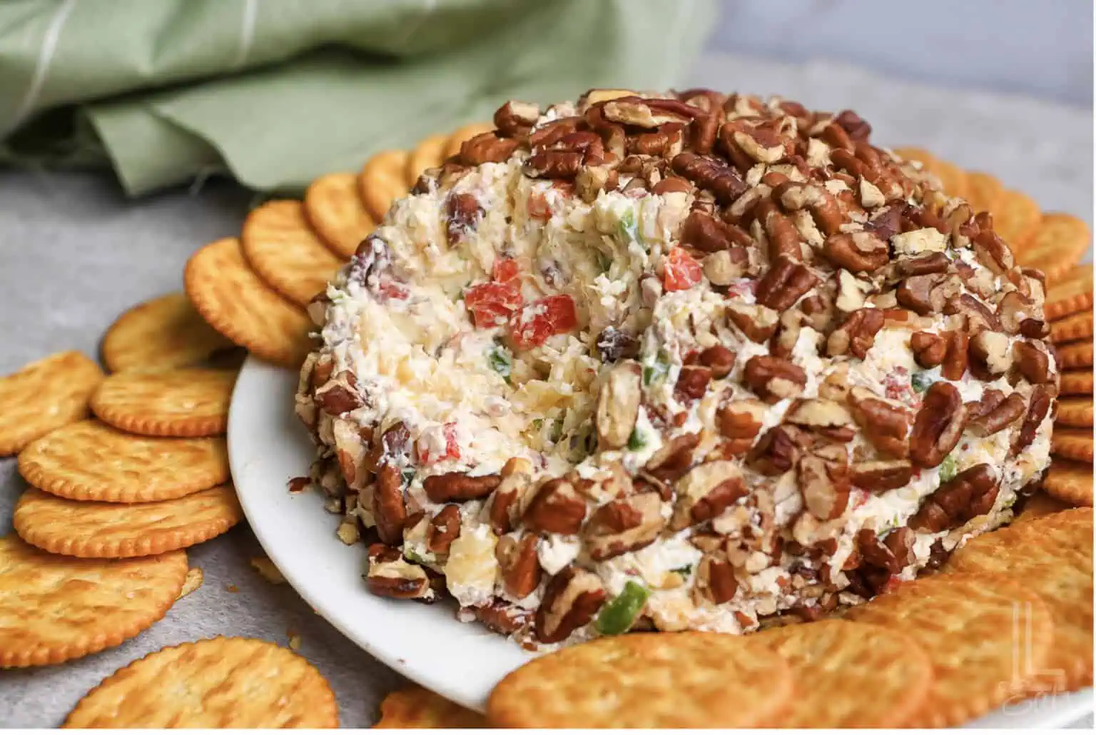 pineapple cheese ball covered in pecans, with portion missing.