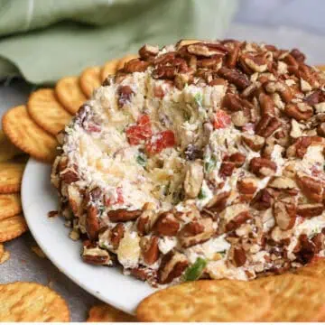 pineapple cheese ball covered in pecans, with portion missing.