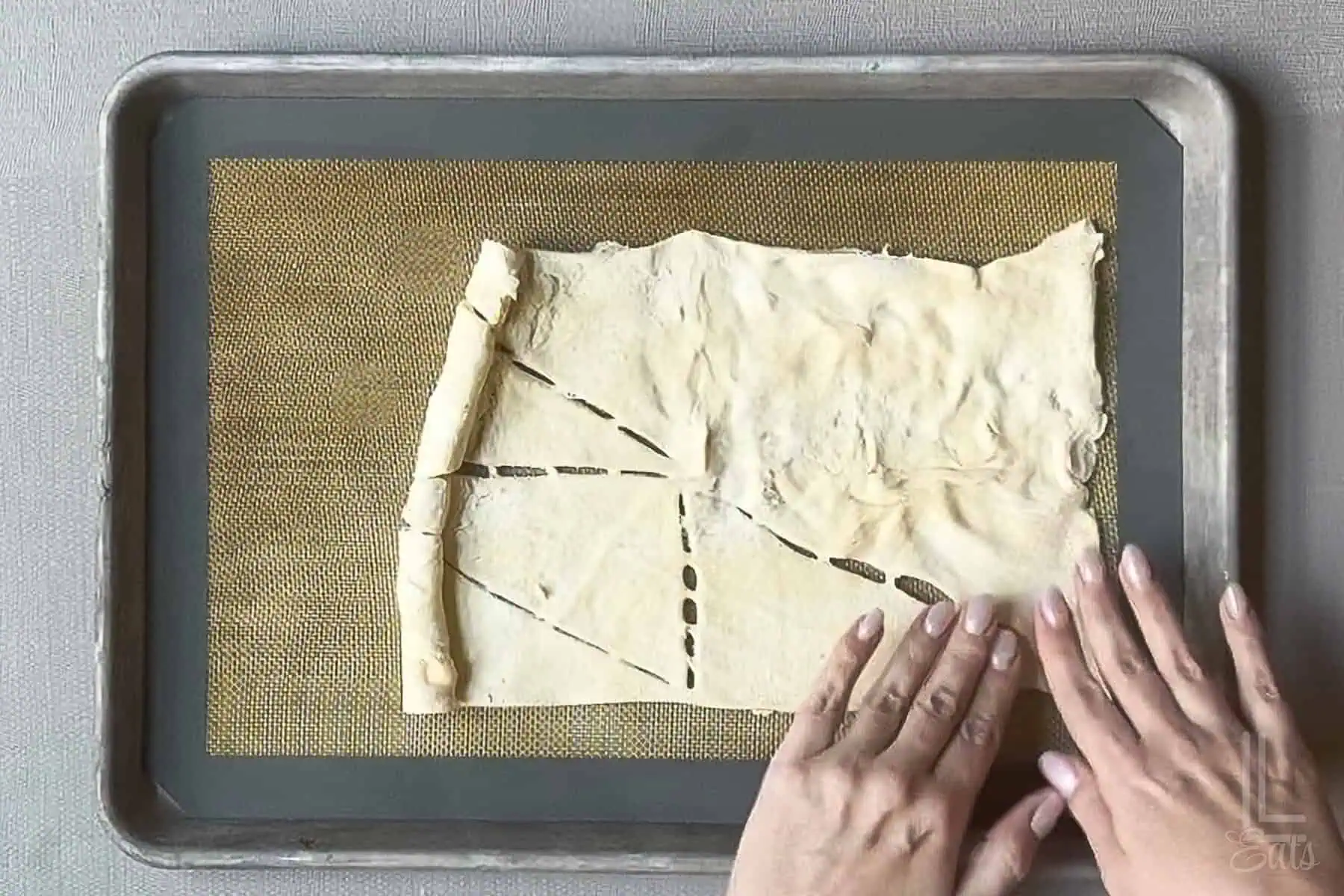 Pressing crescent roll dough seams together to form a rectangle.