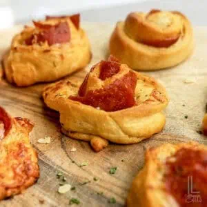 pizza roll ups with pepperoni on a cuting board.