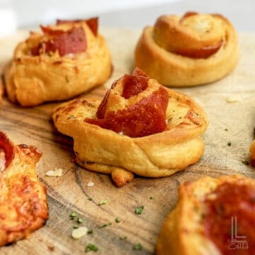 pizza roll ups with pepperoni on a cuting board.
