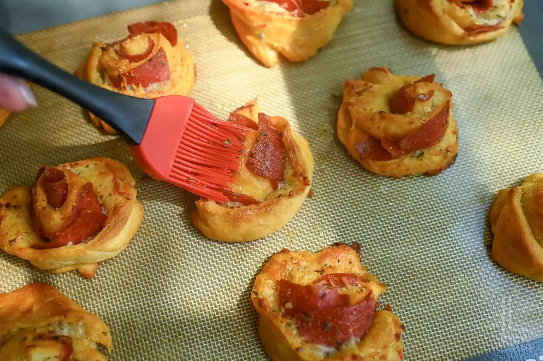Baked pizza roll ups with crispy edges brushed with garlic butter.