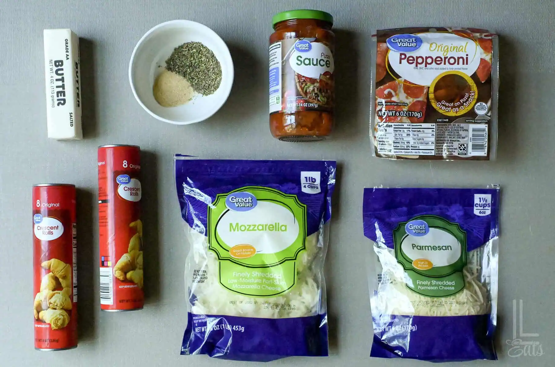 ingredients for pizza roll ups, including crescent roll dough, cheese, and pepperoni.