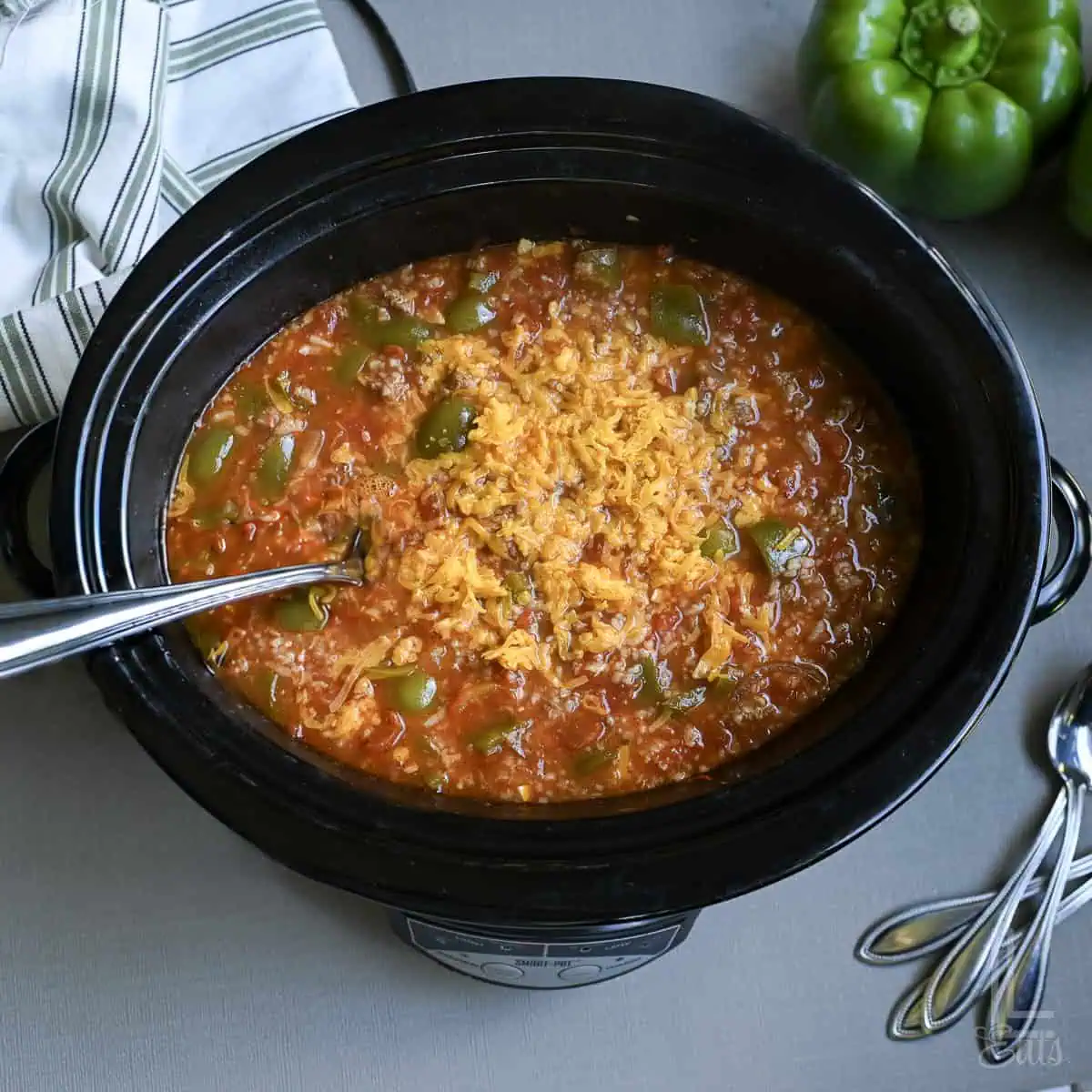 Slow cooker filled with stuffed pepper soup with green peppers and rice.