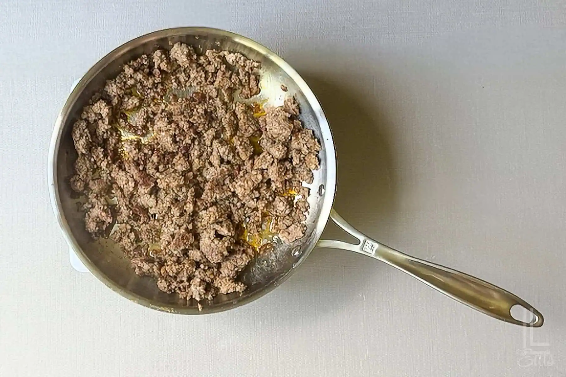 Browned breakfast sausage in a skillet for stuffed pepper soup.