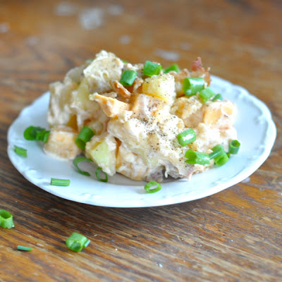 twice baked potato salad on a white plate, covered in green onions.
